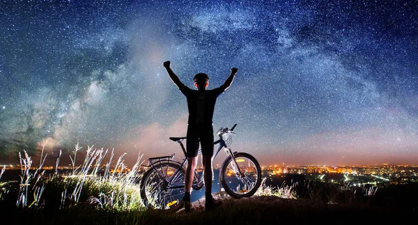 Kerékpáros, kerékpáros, az éjszaka csillagos ég alatt — Stock Fotó