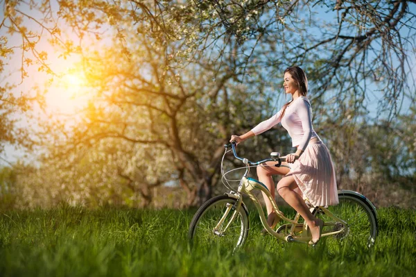 Beautiful female cyclist with retro bicycle in the spring garden — Stock Photo, Image