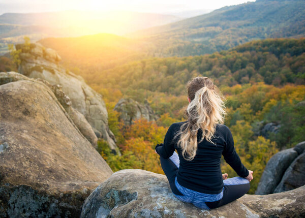 Sporty fit woman is practicing yoga on the top of the mountain