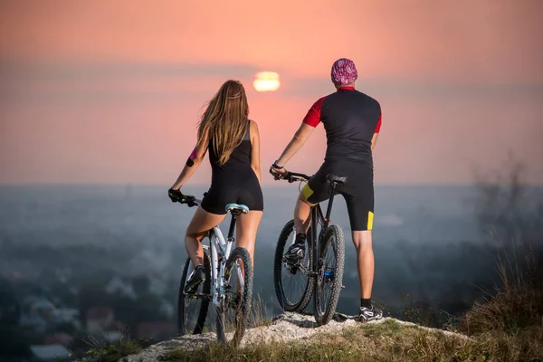 Radfahrerpaar mit Mountainbikes auf dem Hügel bei Sonnenuntergang — Stockfoto