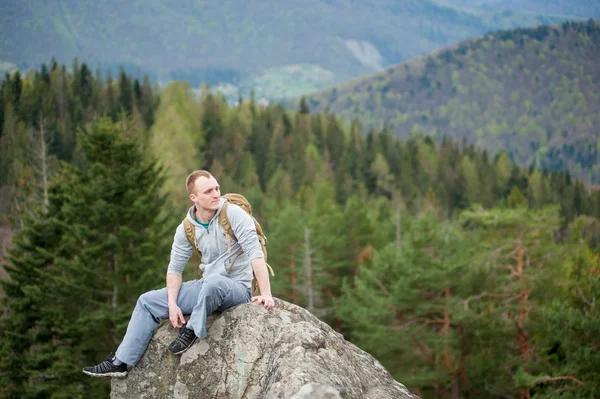 Mężczyzna wspinacz z brązowy plecak na szczycie skały — Zdjęcie stockowe