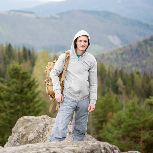 Male climber with brown backpack on the peak of rock — Stock Photo, Image