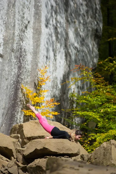 Donna in forma sportiva sta praticando yoga sul masso nella natura — Foto Stock