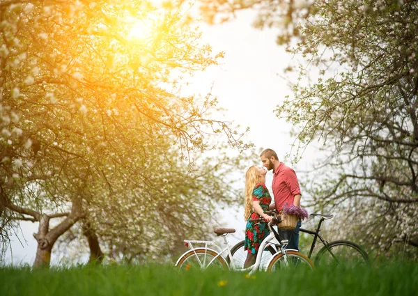 Amantes pareja joven con bicicletas en el jardín de primavera — Foto de Stock