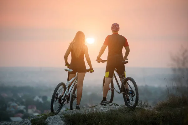 Couple bicyclist with mountain bikes on the hill at sunset — Stock Photo, Image