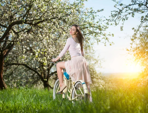 Beautiful female cyclist with retro bicycle in the spring garden — Stock Photo, Image