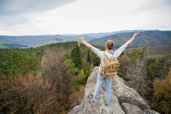 Escalador masculino con mochila marrón en la cima de la roca — Foto de Stock