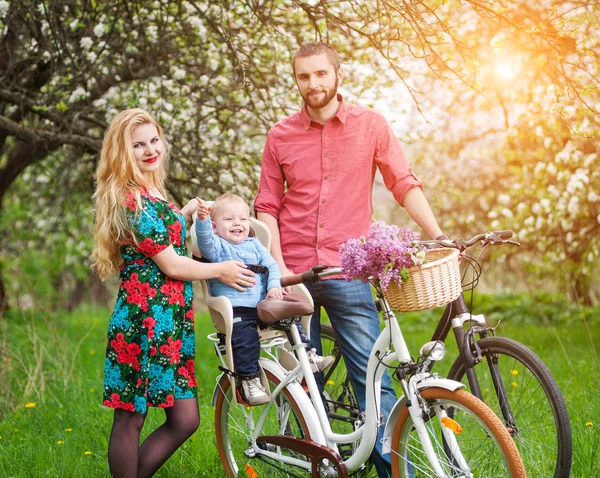 Молода сім'я на велосипедах у весняному саду — стокове фото