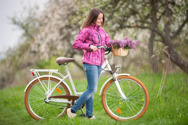 Ciclista femenina con bicicleta blanca vintage en jardín de primavera — Foto de Stock