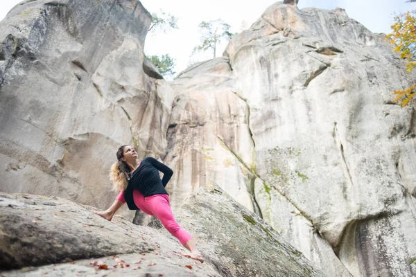 Mujer deportiva en forma está practicando yoga en la roca en la naturaleza — Foto de Stock