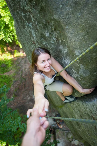 Rockclimber helping to female climber to reach top of mountain — Stock Photo, Image