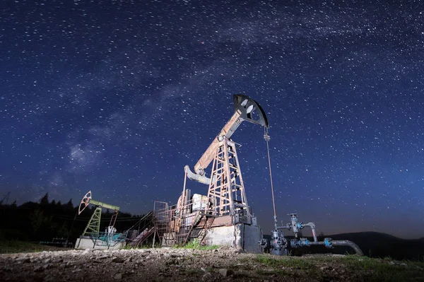 Нефтяные насосы на нефтяном месторождении ночью — стоковое фото
