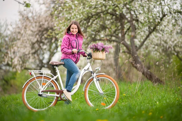 Ciclista femenina con bicicleta blanca vintage en jardín de primavera — Foto de Stock