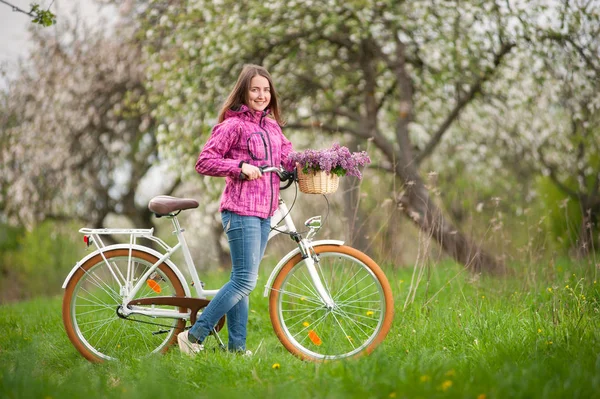 Female cyclist with vintage white bicycle in spring garden — Stock Photo, Image