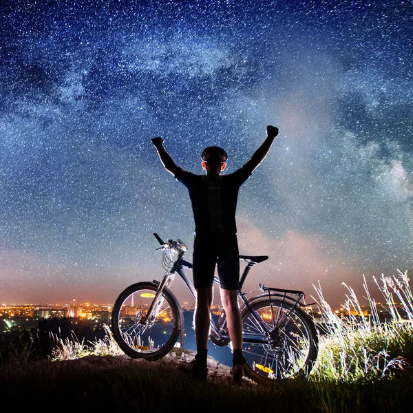 Cyclist with bike in the night under starry sky