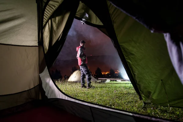 Young man standing near night camping — Stock Photo, Image