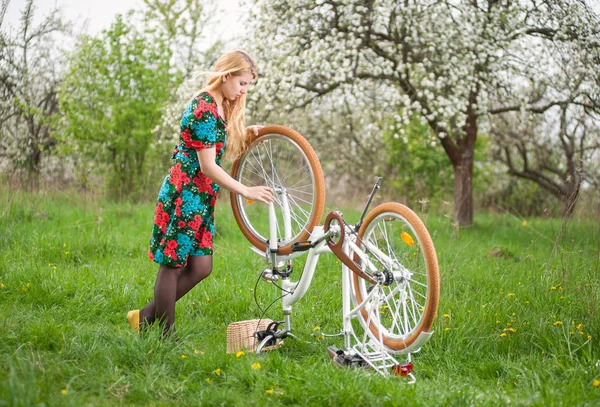 Велосипедистка с винтажным белым велосипедом в весеннем саду — стоковое фото