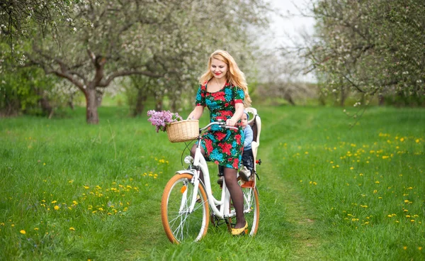 Blonde female riding city bicycle with baby in bicycle chair — Stock Photo, Image