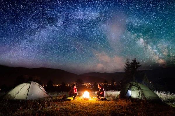 Couple romantique assis au feu de camp près des tentes dans la nuit — Photo