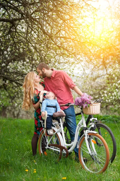 Молода сім'я на велосипедах у весняному саду — стокове фото
