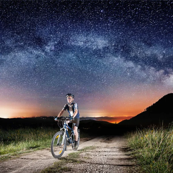 Ποδηλάτης ιππασίας ποδήλατο το βράδυ κάτω από τον έναστρο ουρανό — Φωτογραφία Αρχείου