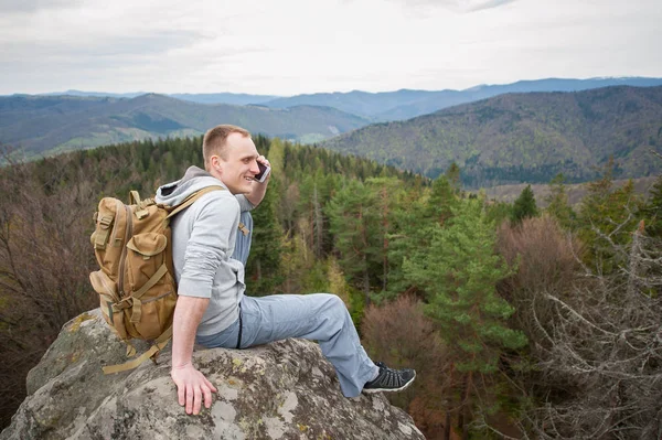 岩の頂上に茶色のバックパックで男性登山者 — ストック写真