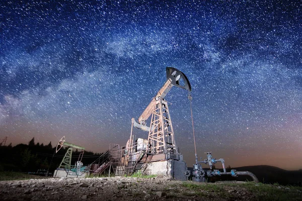 Нефтяные насосы на нефтяном месторождении ночью — стоковое фото