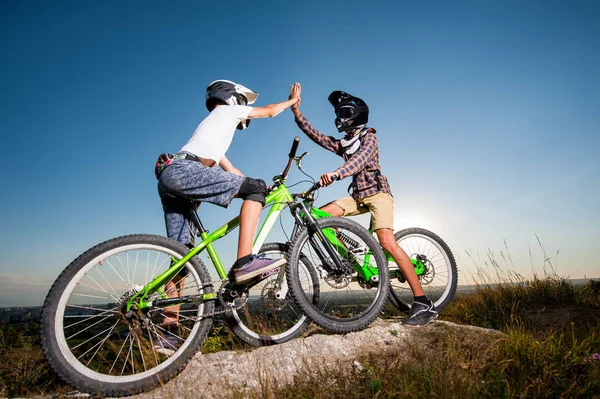 Radfahrer mit Mountainbikes auf dem Hügel unter blauem Himmel — Stockfoto