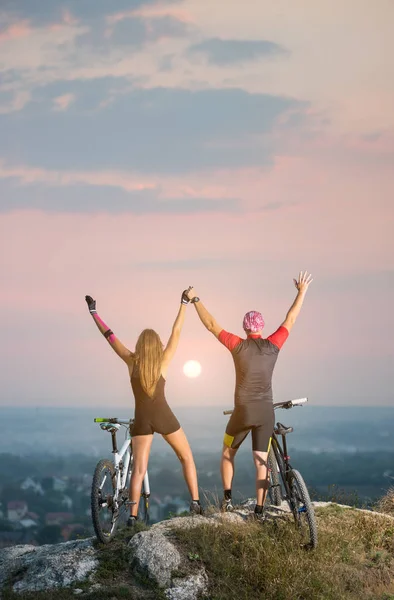 Пара велосипедист з гірськими велосипедами на пагорбі на заході сонця — стокове фото