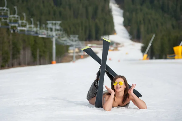쾌활 한 벌 거 벗은 여성 스키 리조트에서 스키 리프트 가까운 눈 덮인 슬로프에 누워 — 스톡 사진