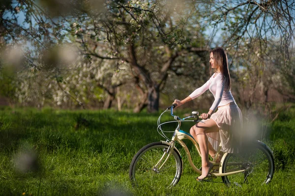 Schöne Radfahrerin mit Retro-Fahrrad im Frühlingsgarten — Stockfoto