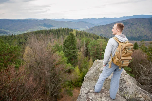 Escalador masculino con mochila marrón en la cima de la roca — Foto de Stock