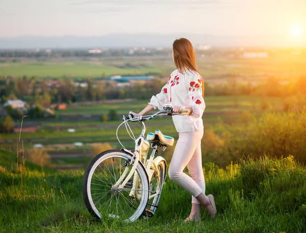 Mujer con bicicleta retro en la colina por la noche — Foto de Stock