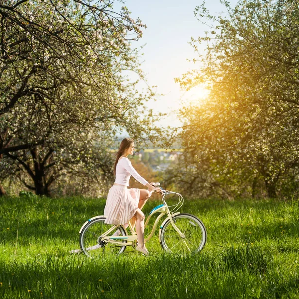 Beautiful female cyclist with retro bicycle in the spring garden — Stock Photo, Image