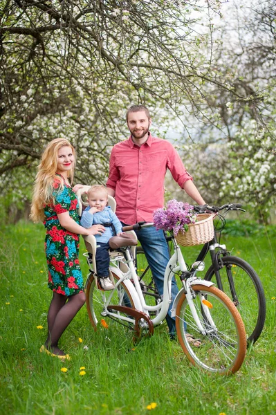 Young family on a bicycles in the spring garden