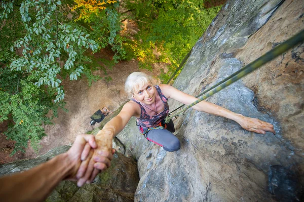 Rockclimber 산의 상단에 도달 여성 산악인에 도움 — 스톡 사진