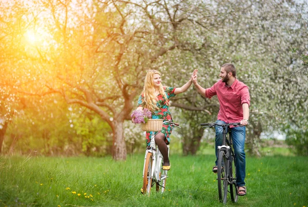 爱骑自行车春天的花园里的年轻夫妇 — 图库照片