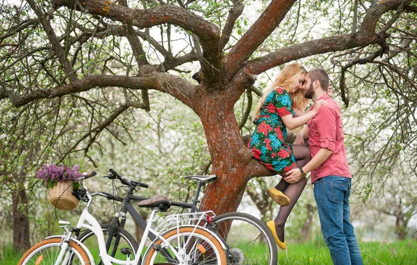 봄 정원에서 자전거와 함께 사랑 하는 젊은 부부 — 스톡 사진