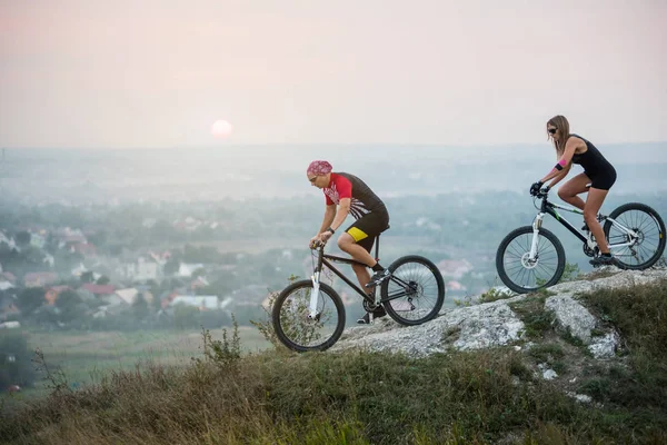 Radfahrerpaar mit Mountainbikes auf dem Hügel bei Sonnenuntergang — Stockfoto