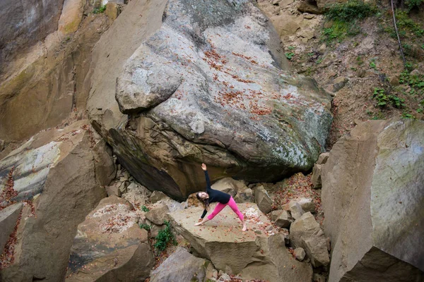 Mujer deportiva en forma está practicando yoga en la roca en la naturaleza — Foto de Stock