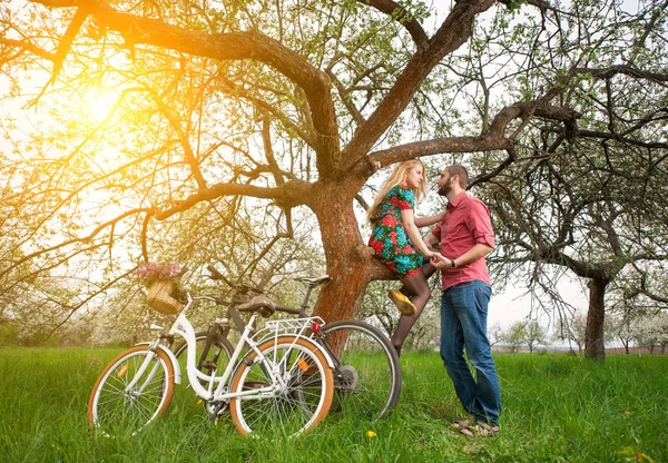 Любляча молода пара з велосипедами у весняному саду — стокове фото