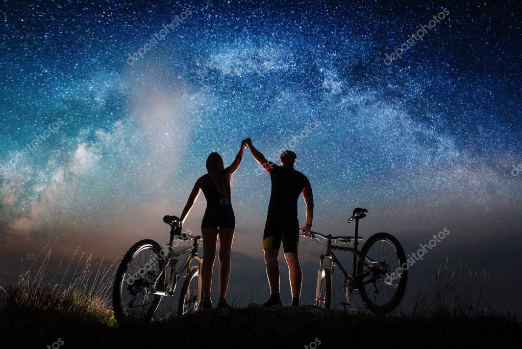 Pareja de ciclistas con bicicletas de montaña en la noche bajo el