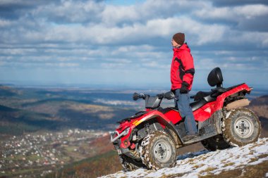 Kış giysileri quad bisiklet üzerinde duran adam 