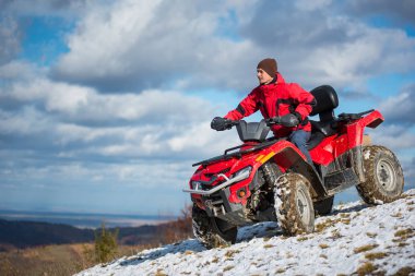 Kırmızı dört tekerlekli quad bisiklet üzerinde kişini