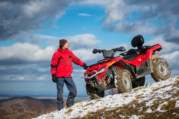adamın yanına atv karlı bir tepe üzerinde