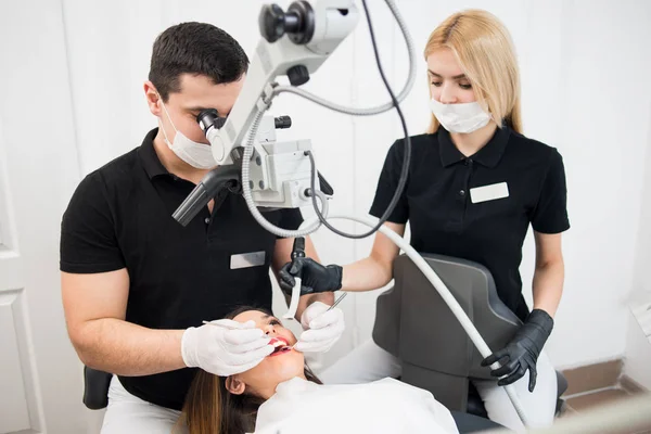 Dentist and assistant treating patient teeth