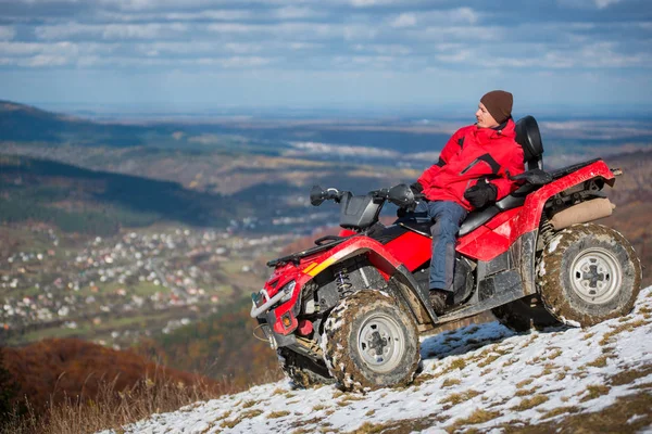 Kırmızı bir quad bisiklet üzerinde oturan adam 