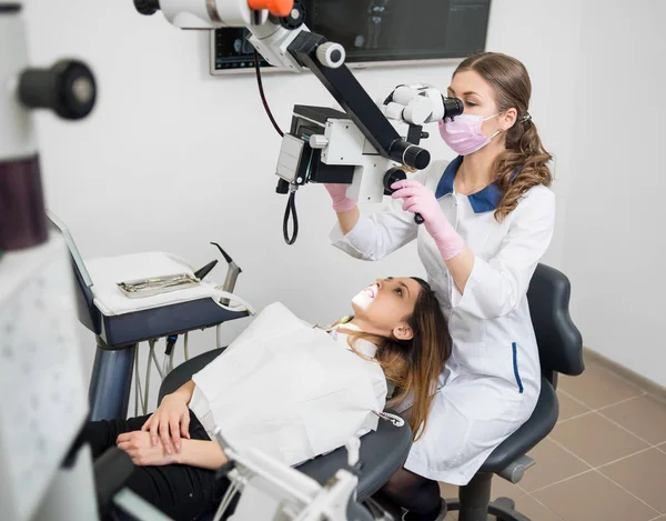 Έλεγχος ασθενής γυναίκα οδοντίατρος με μικροσκόπιο — Φωτογραφία Αρχείου