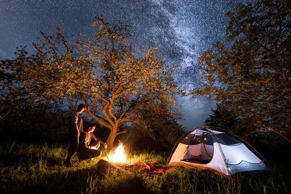 Par turister på en lägereld nära tält — Stockfoto