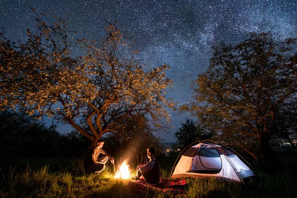 Turistas casal em uma fogueira perto da tenda — Fotografia de Stock